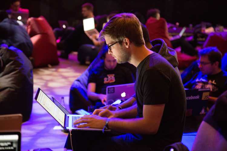 A man sits working with a laptop on his lap.