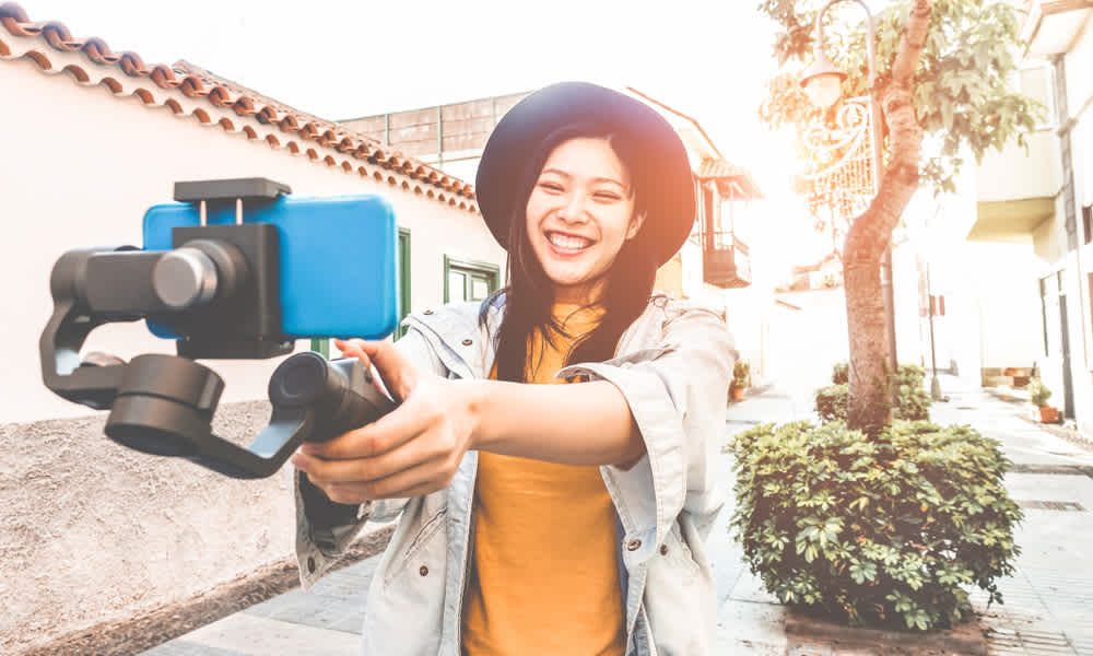 Happy asian woman vlogging with gimbal tripod and smartphone - Influencer chinese girl having fun with new trend technology - Millennial generation activity job, youth and tech concept - Focus on face
