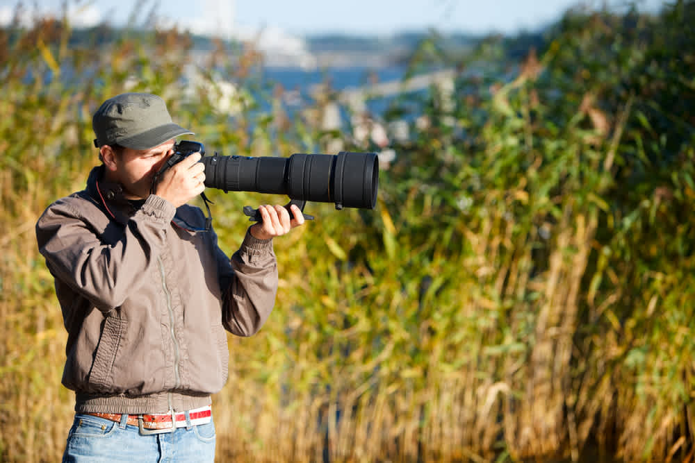 Young photographer taking photos using telephoto lens