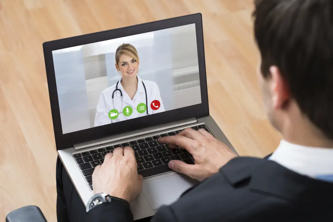 Businessperson Videochatting Online With Doctor On Laptop