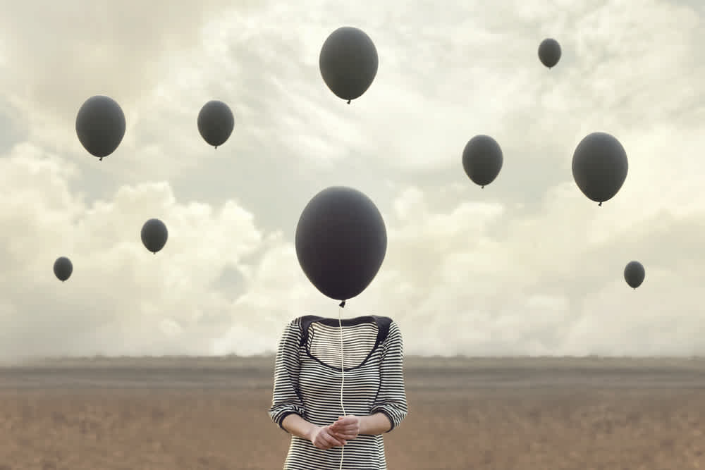 surreal image of woman and blacks balloons flying
