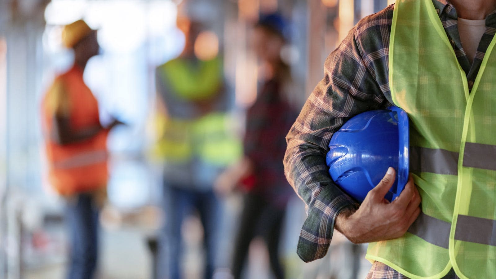 En mann holder en beskyttelseshjelm på en arbeidsplass