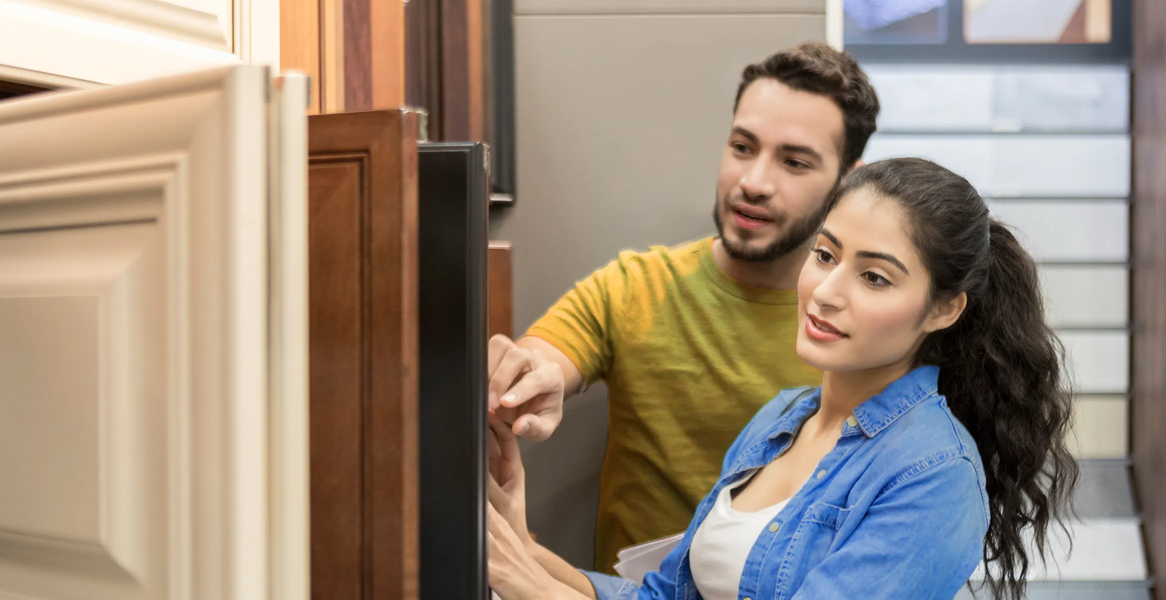 A couple looks through cabinet door samples in a home improvement store.