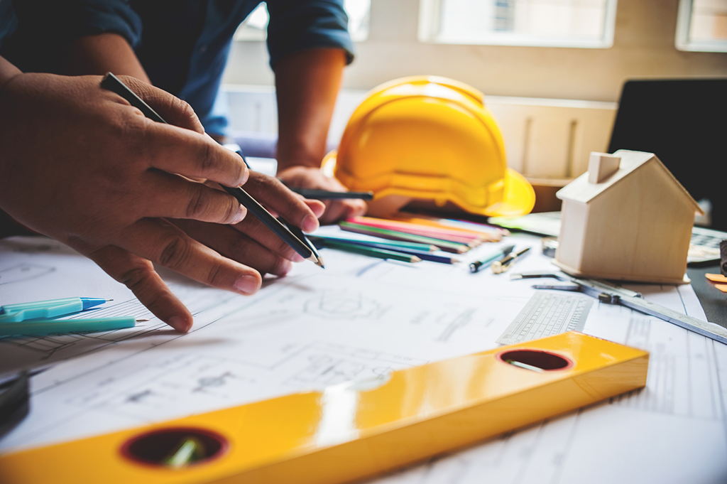 Deux ouvriers de la construction sont penchés sur une table de travail et examinent un document.