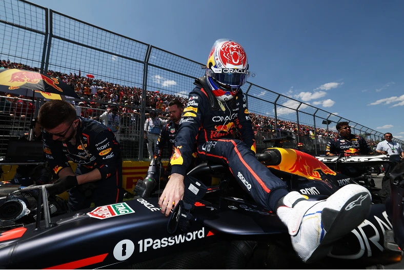 An Oracle Red Bull Racing driver climbs into the cockpit before a race, as the team makes final preparations showcasing precision, trust, and seamless coordination.