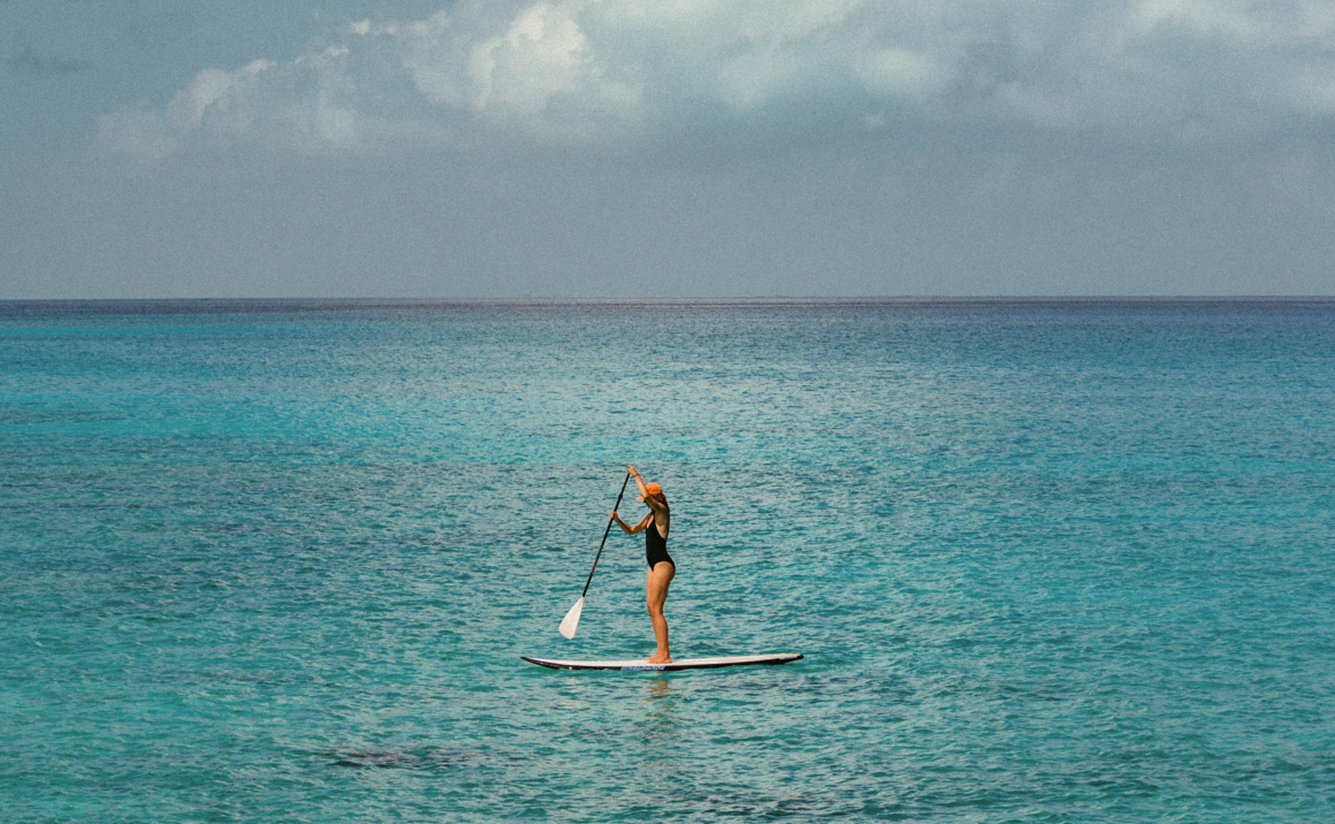 Guest paddleboarding on turquoise Caribbean waters during a luxury yacht cruise aboard Amangati