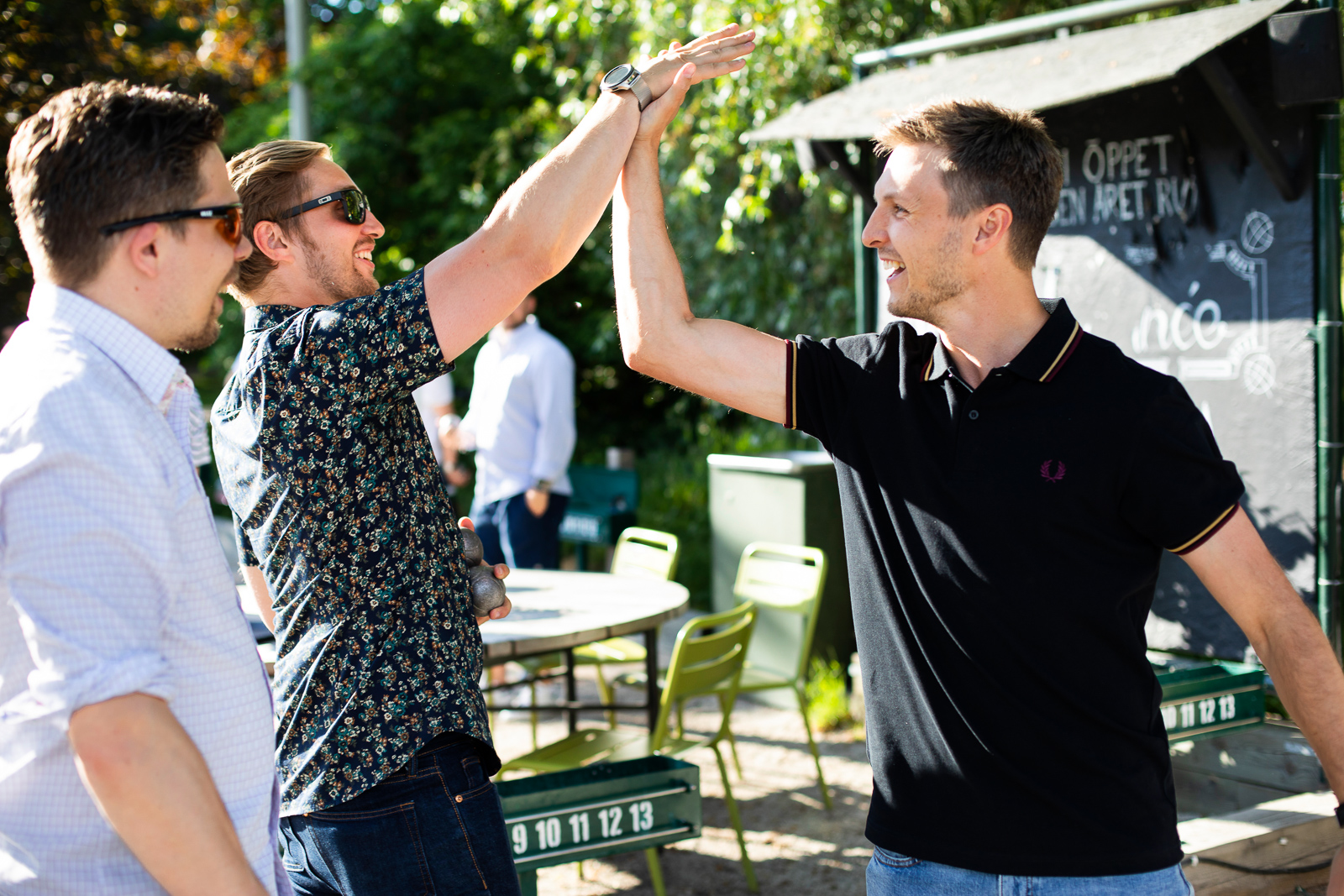 Tre män i utomhusmiljö varav två som gör en high-five