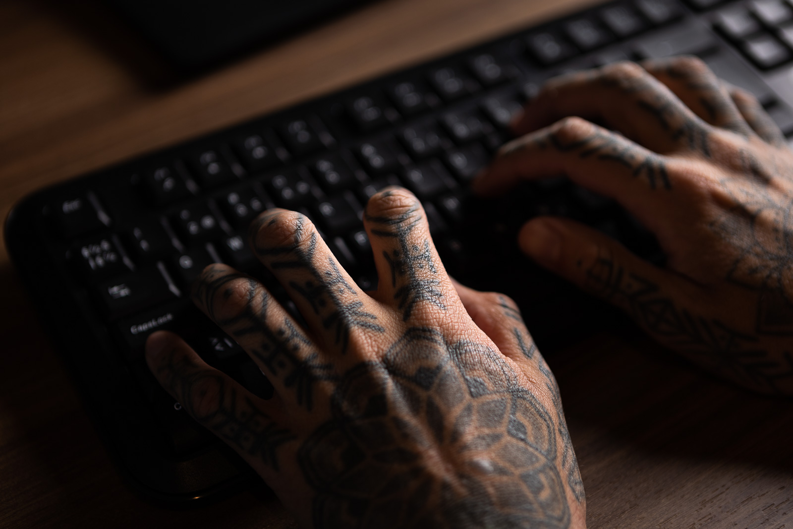 Tatuerade händer på ett svart tangentbord