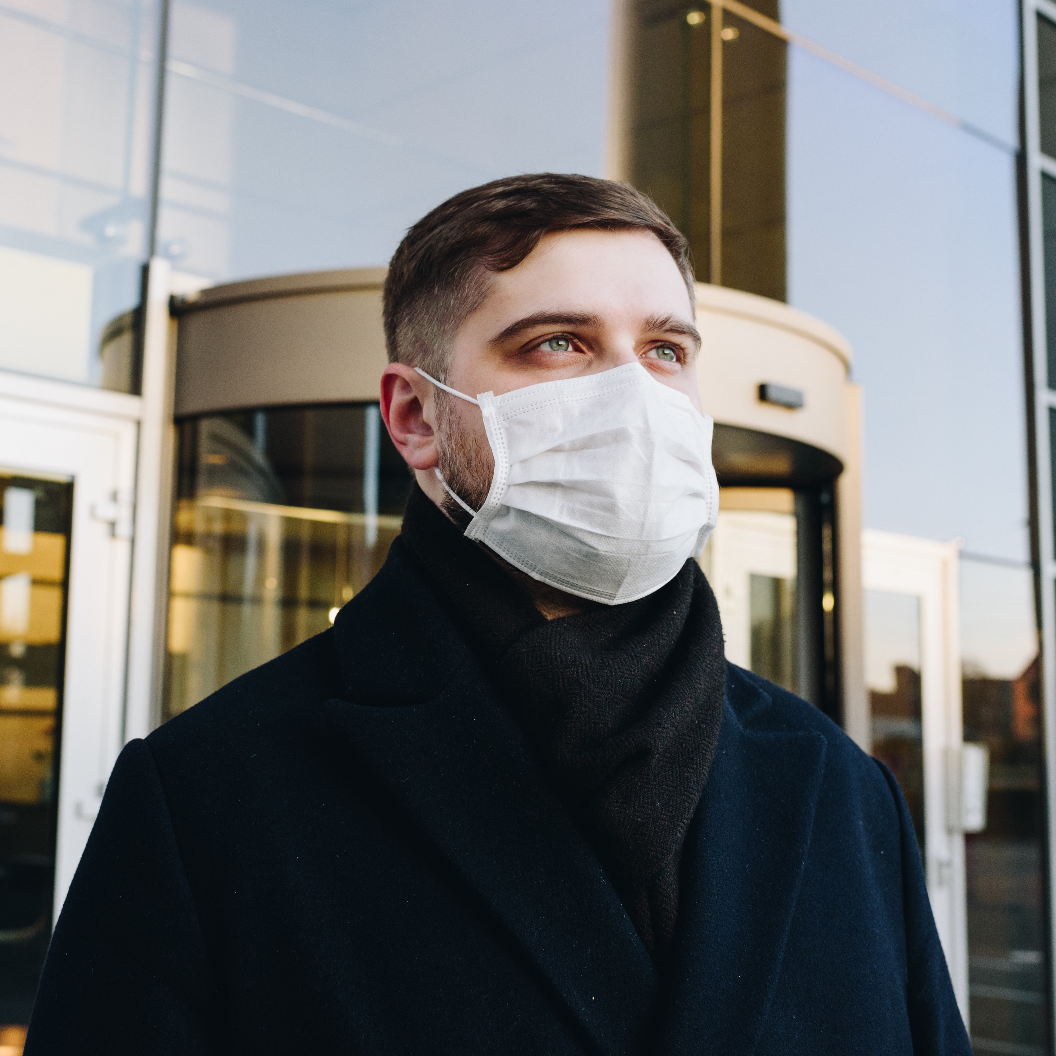 Man with protective mask standing in front of office builiding