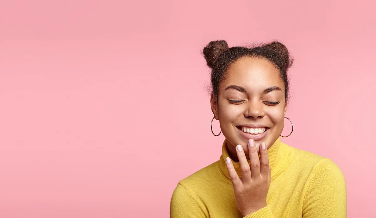 Woman in front of a pink background laughing Clairerightside