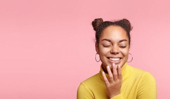 Woman in front of a pink background laughing Clairerightside