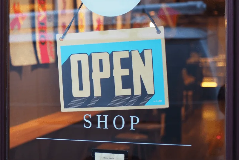 A glass shop door with a bright blue sign with this text: "OPEN"