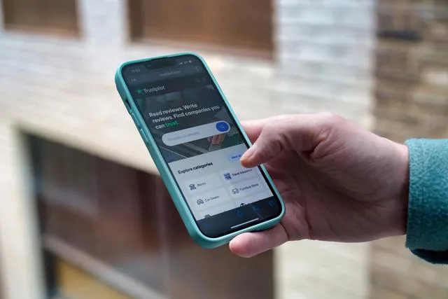 A man holding a phone open on the Trustpilot homepage How to choose a mortgage broker