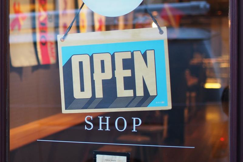 A shop glass door with a bright blue sign with the text: "OPEN"