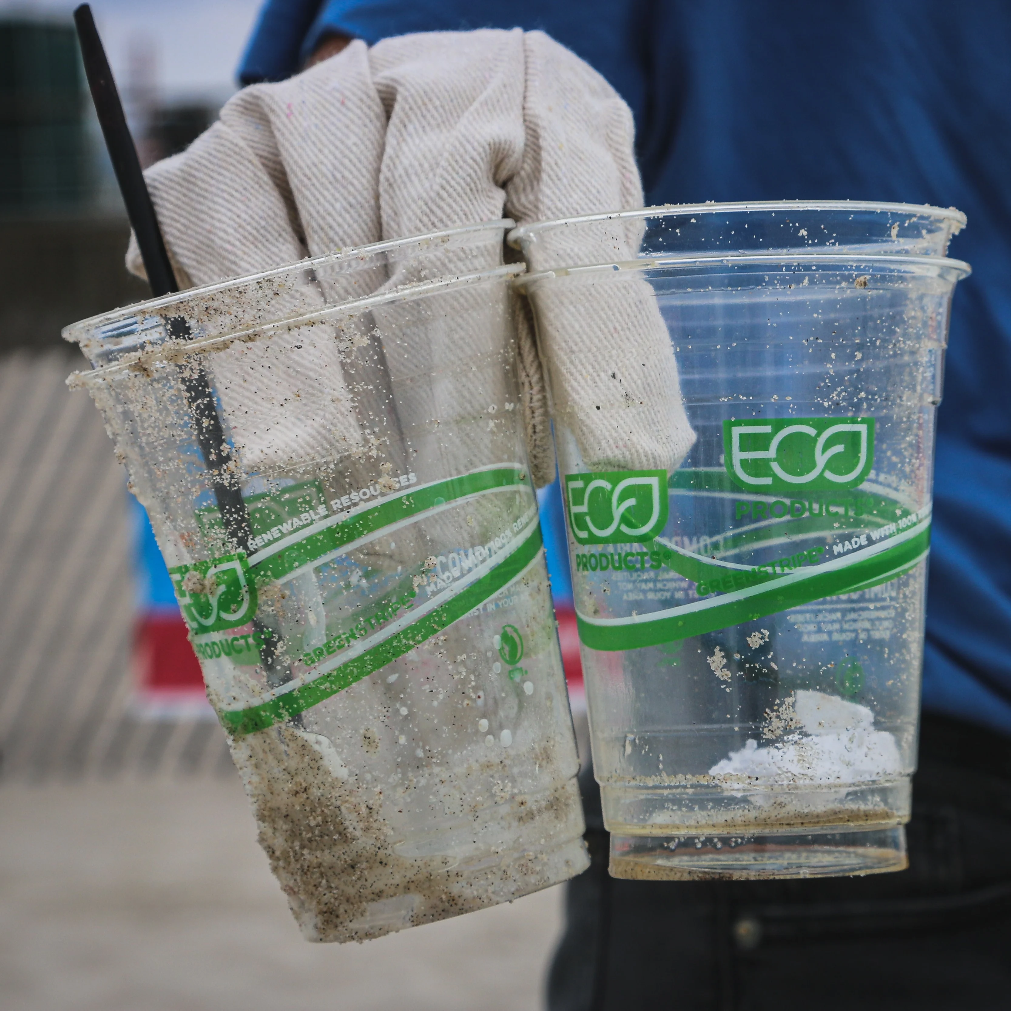Gloved hand holds plastic beer glasses labelled "ECO"
