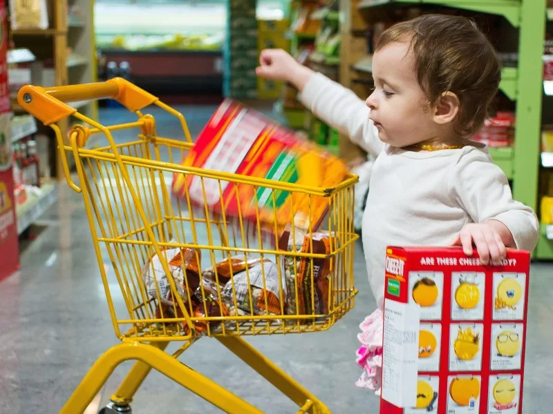 A baby puts supermarket goods in a shopping cart