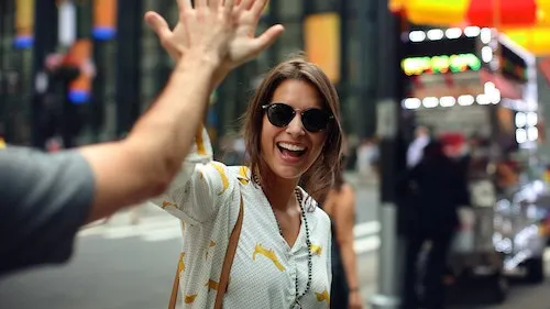 Picture of a woman with sun glasses smiling while she gives high five
