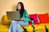A woman sitting on a couch looking at her laptop Romance scams