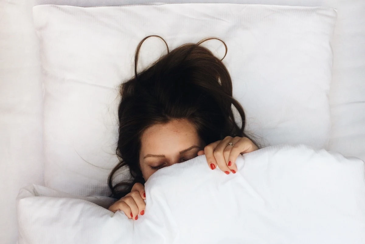 foto di donna che dorme sotto le coperte
