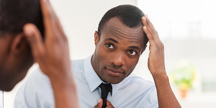 Man looking in mirror and touching hair