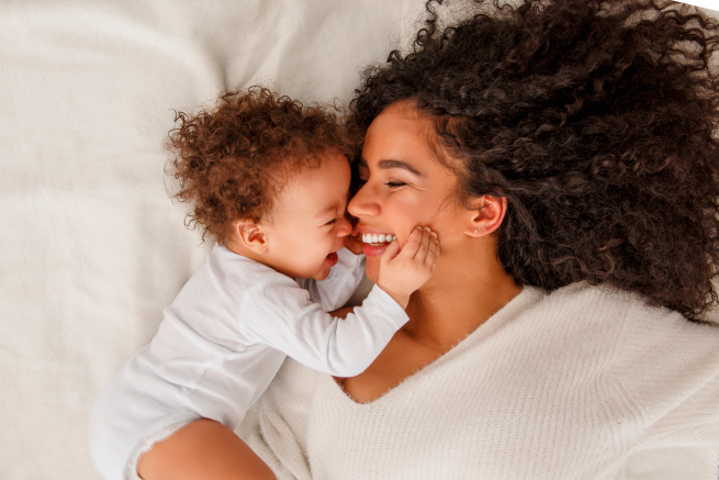 Smiling baby holding their mothers face