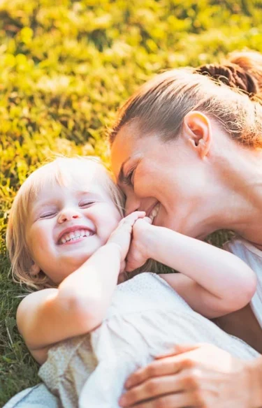 Lady and young girl laying on grass