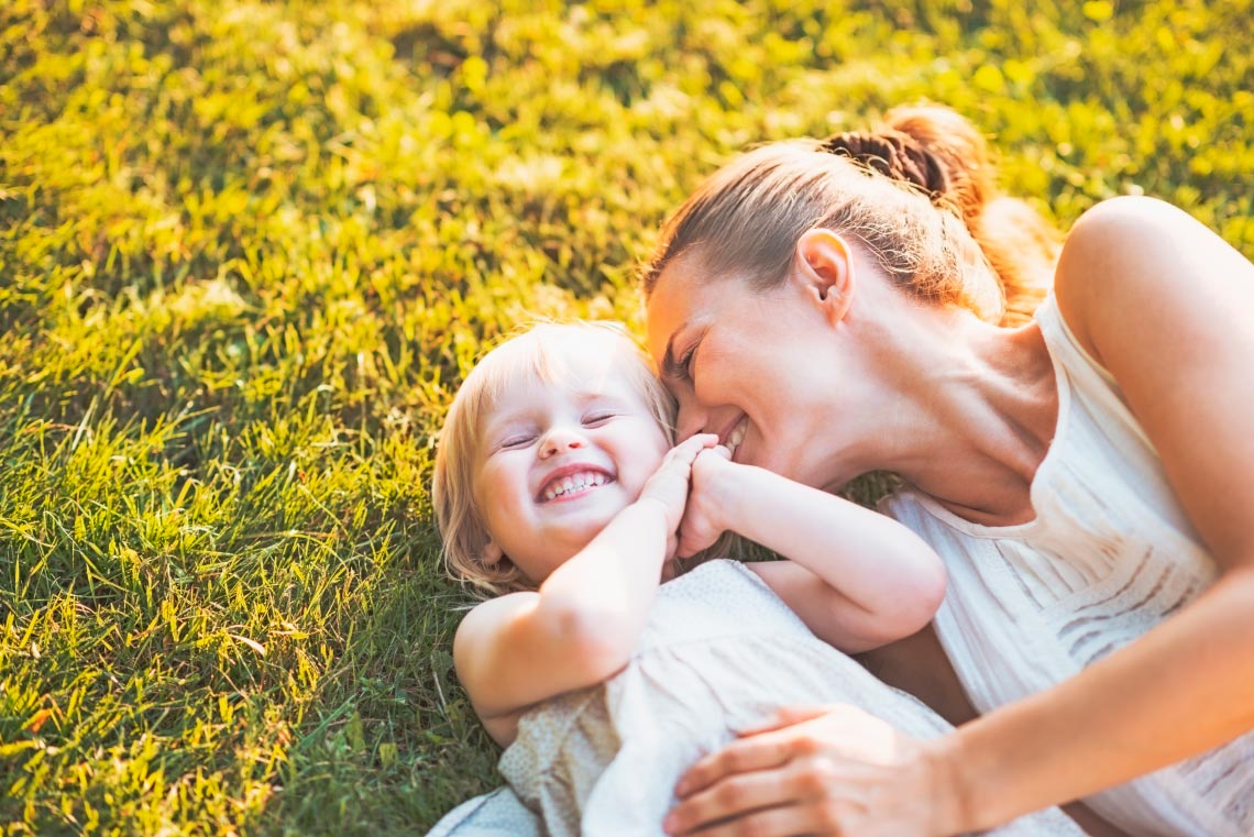 Lady and young girl laying on grass