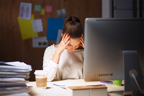 Woman behind computer with lots of documents around