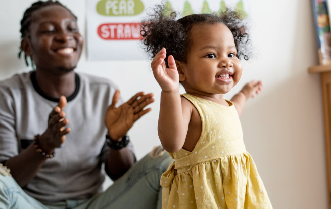 Child dancing with man clapping in the background