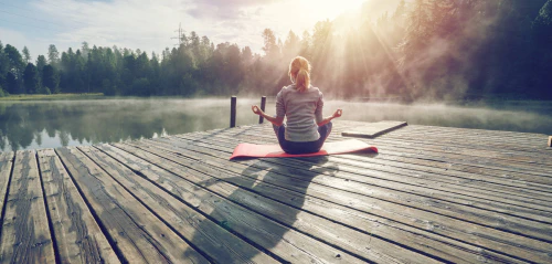 Woman doing yoga by a lake in the morning