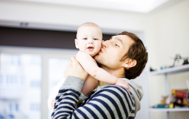 Man kissing a baby in his arms