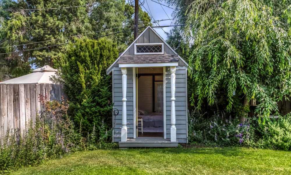 Une mini-chambre d'appoint dans une cabane  en bois, réchauffée par des tissus et des tapis de teinte pastel 