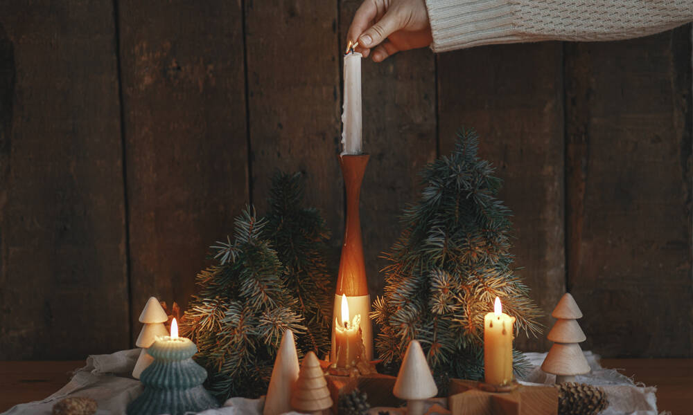 Jolies bougies, mini-sapins et branches de pin pour une scénette de Noël sur un meuble 