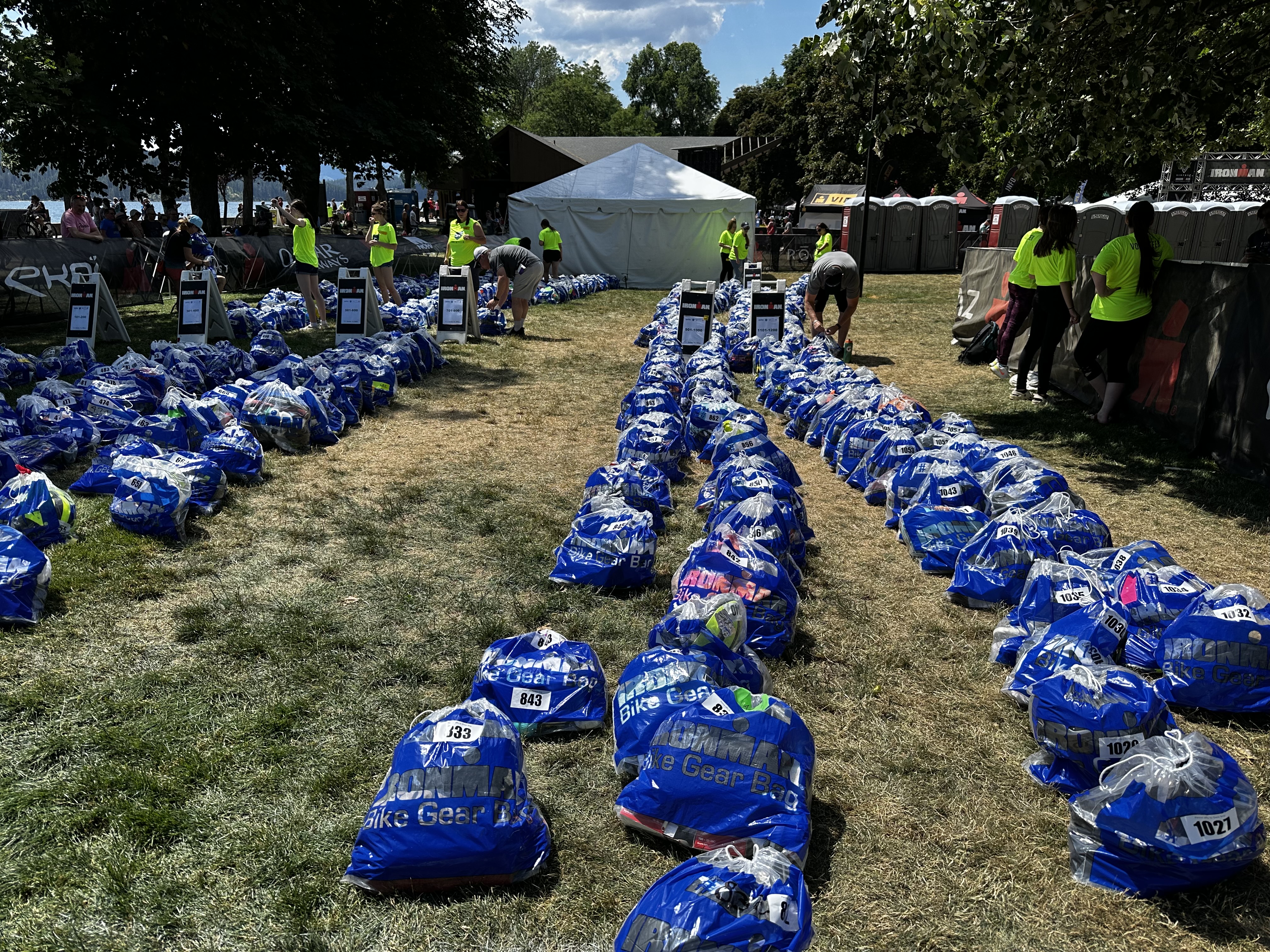 Blue bike gear bags arranged in rows on the ground at the transition area of Ironman Coeur d'Alene.