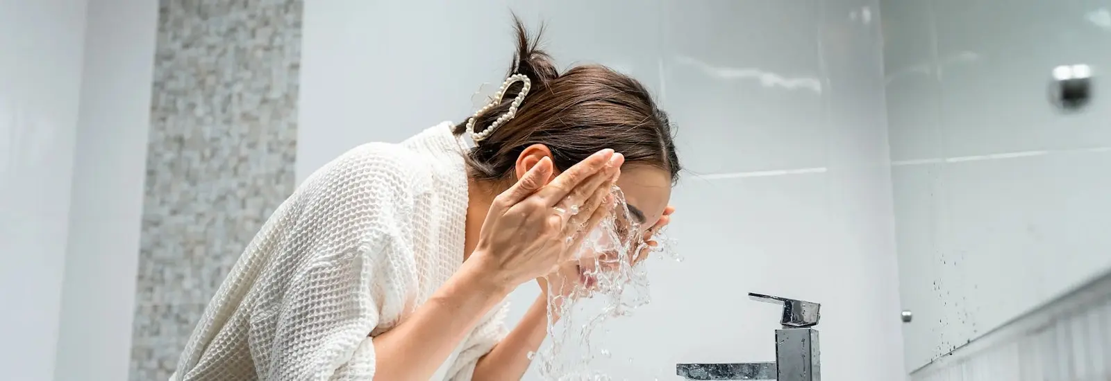 A woman splashes water on her face.