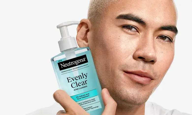Man with clear skin holding a bottle of Neutrogena® Evenly Clear™ Acne Cleanser, mobile, mobile version.