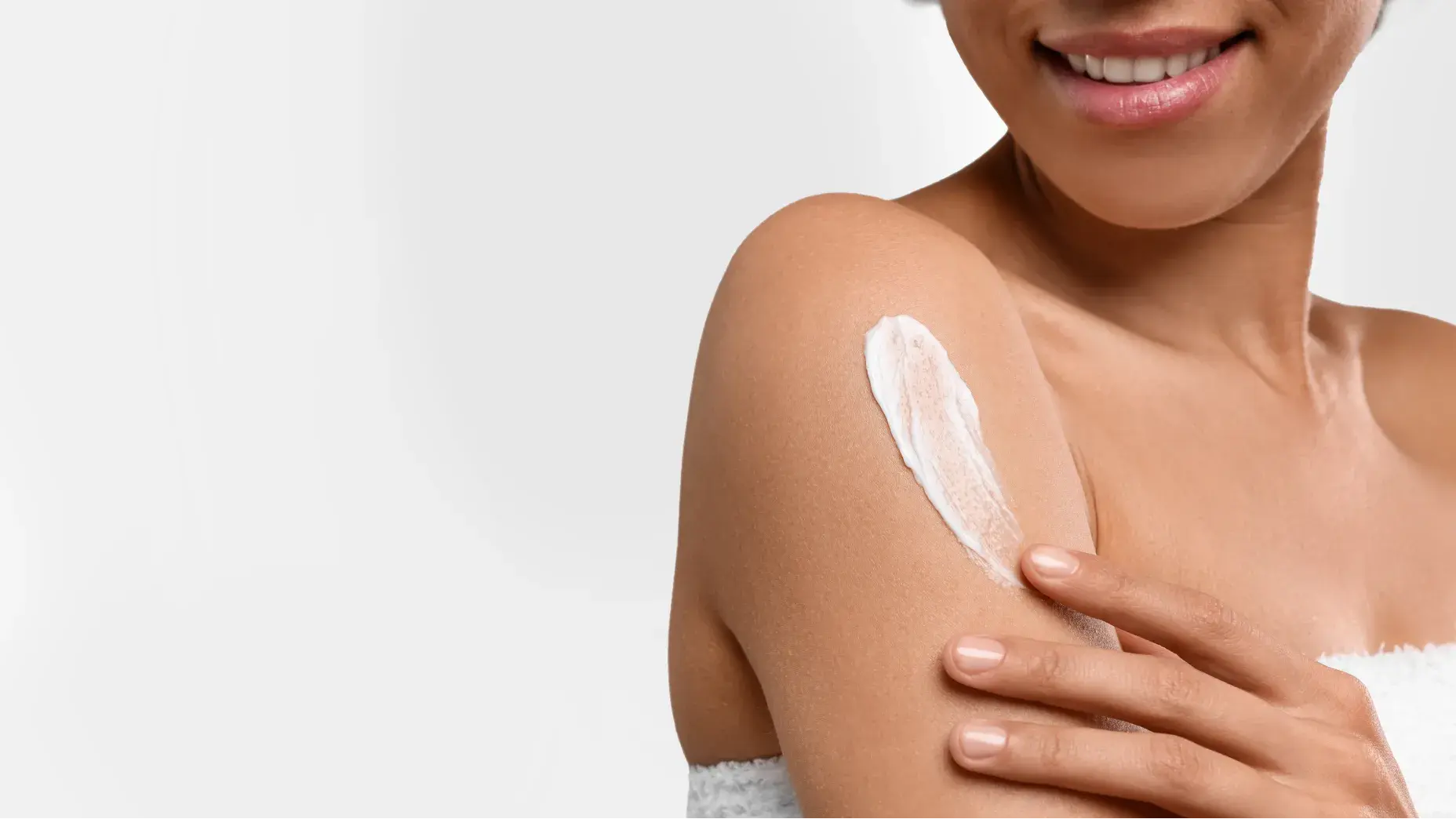 Woman smiling while applying Neutrogena® Sunscreen to arm
