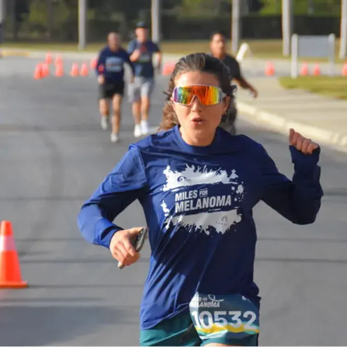 Woman with sunglasses running the Miles for Melanoma race