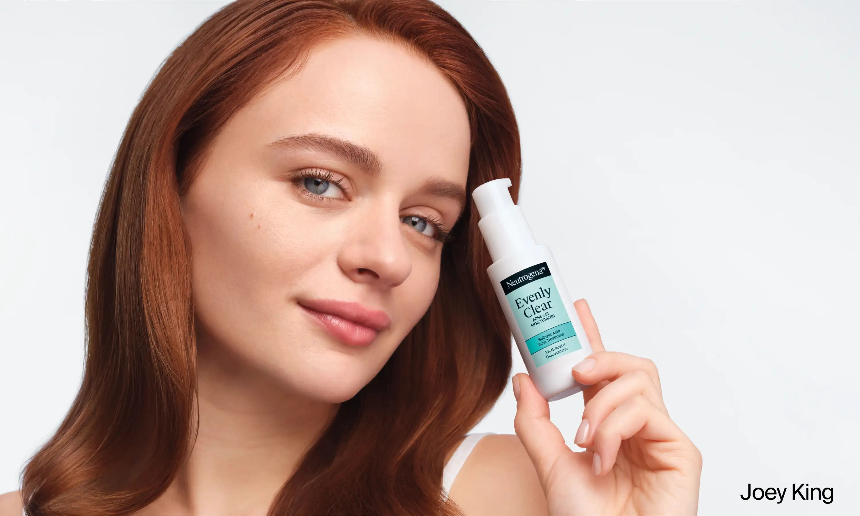Joey King holding a bottle of Neutrogena® Evenly Clear™ Acne Gel Moisturizer