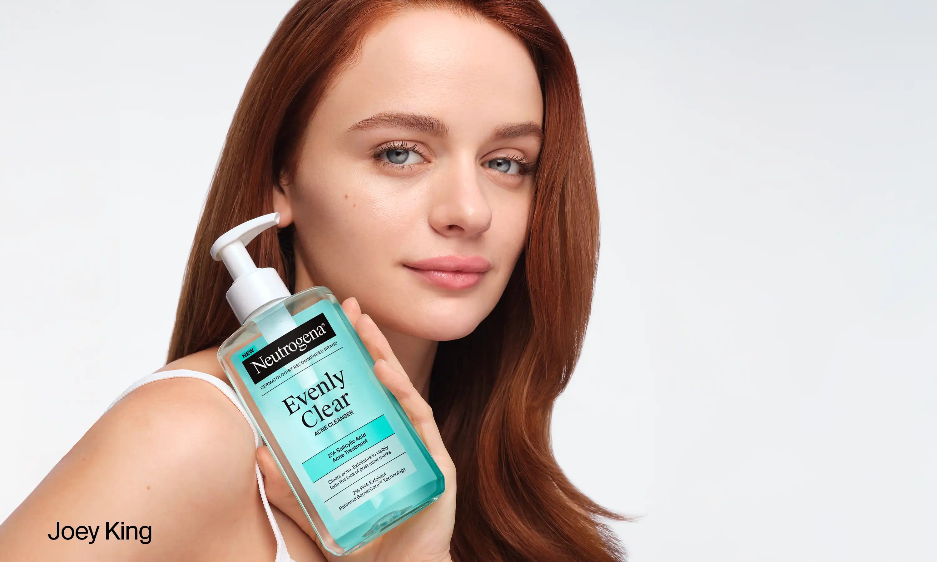 Joey King holding a bottle of Neutrogena® Evenly Clear™ Acne Cleanser