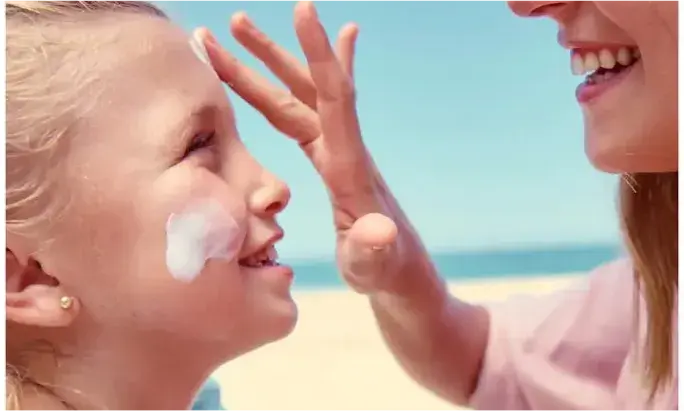 Woman applying Neutrogena® sunscreen to her daughter at the beach