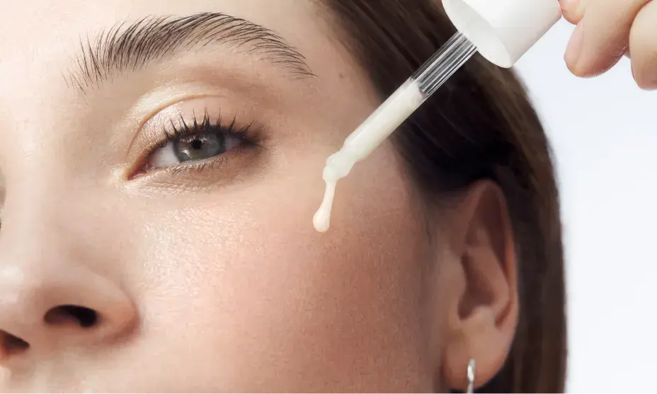 Woman with healthy skin applying dropper full of Rapid Wrinkle Repair® Serum to face