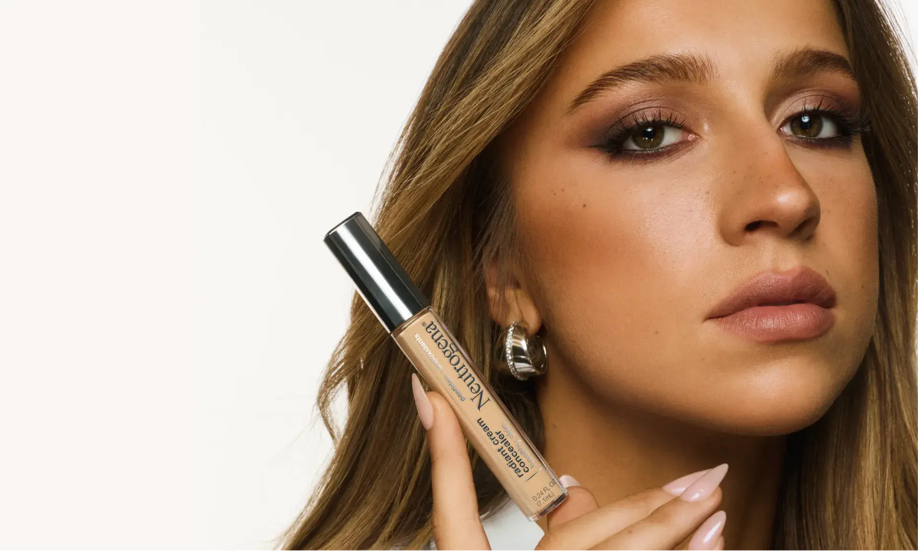 Tate McRae holding a bottle of Neutrogena® Healthy Skin radiant cream concealer