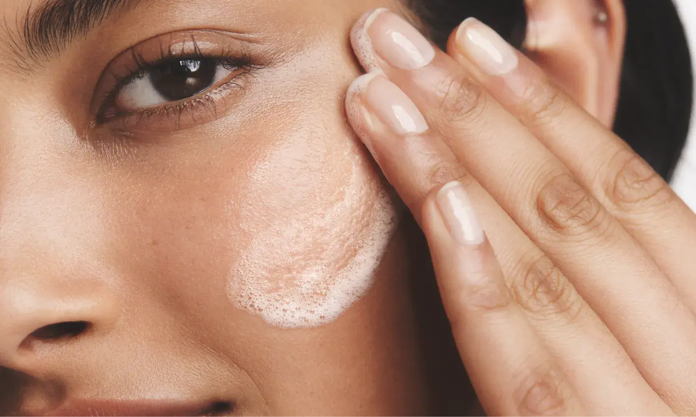 Woman with healthy skin rubbing cleanser on her face