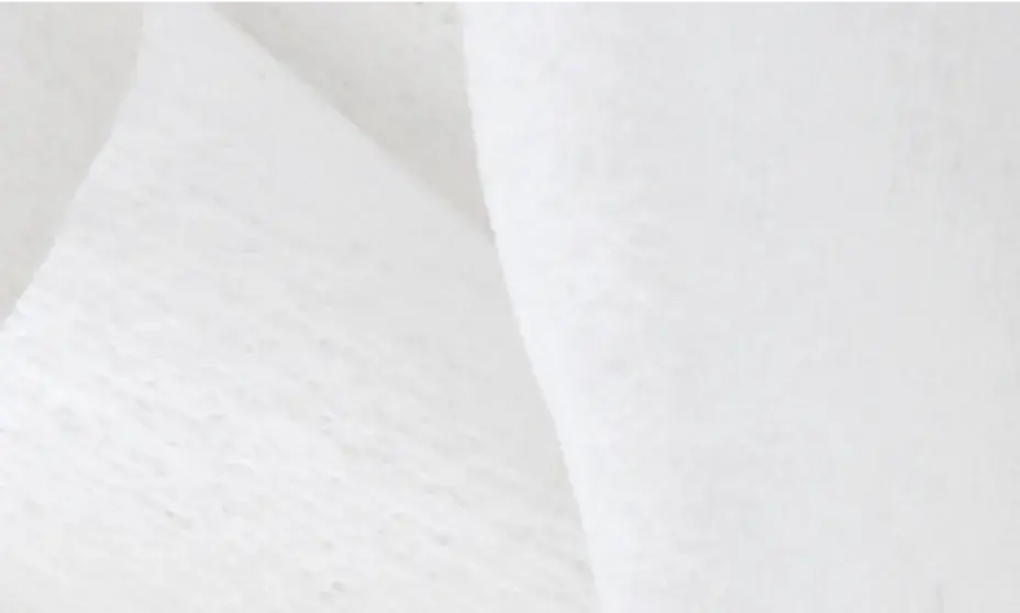 Close-up of a white, textured non-woven fabric, such as a wipe, gauze, or insulation material.