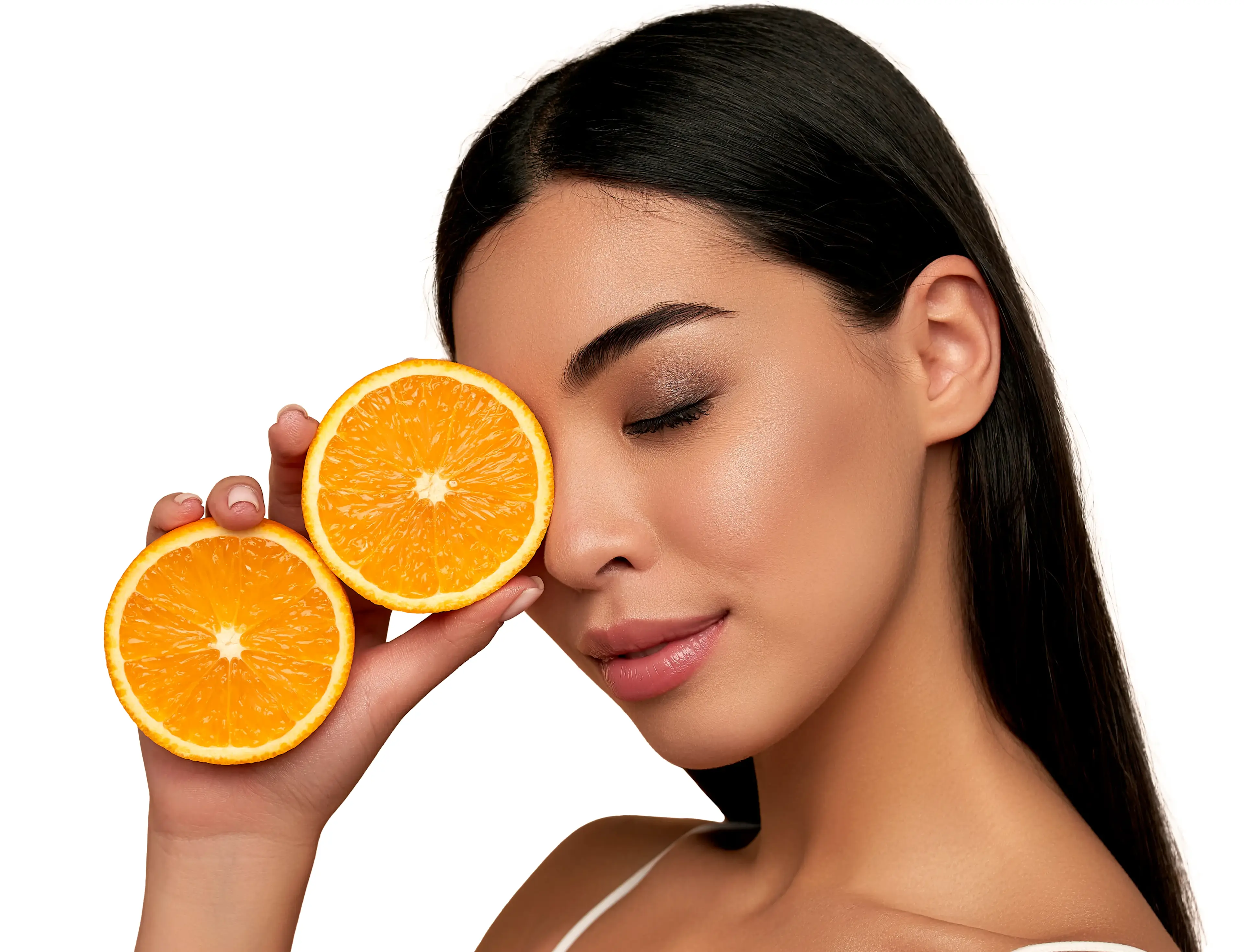 A woman holds half an orange by her face.