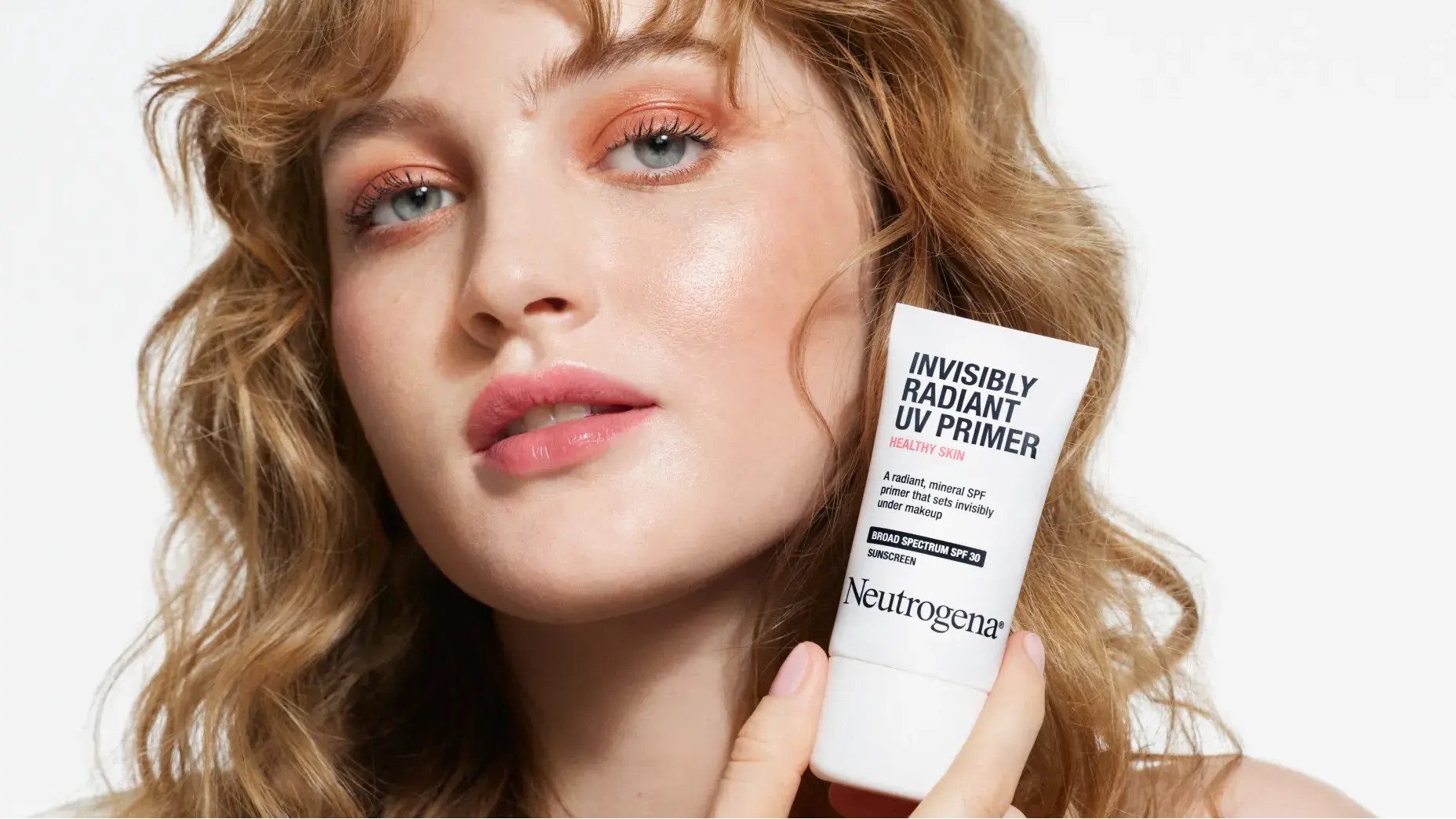 Woman with healthy skin holding Neutrogena® Healthy Skin Invisibly Radiant UV Primer SPF 30