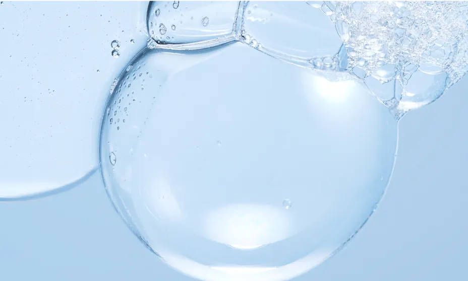 Close-up of a large, translucent water bubble surrounded by a cluster of smaller foam bubbles against a light blue background.