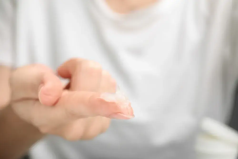 Woman with sample of cosmetic petrolatum on her finger, closeup. 