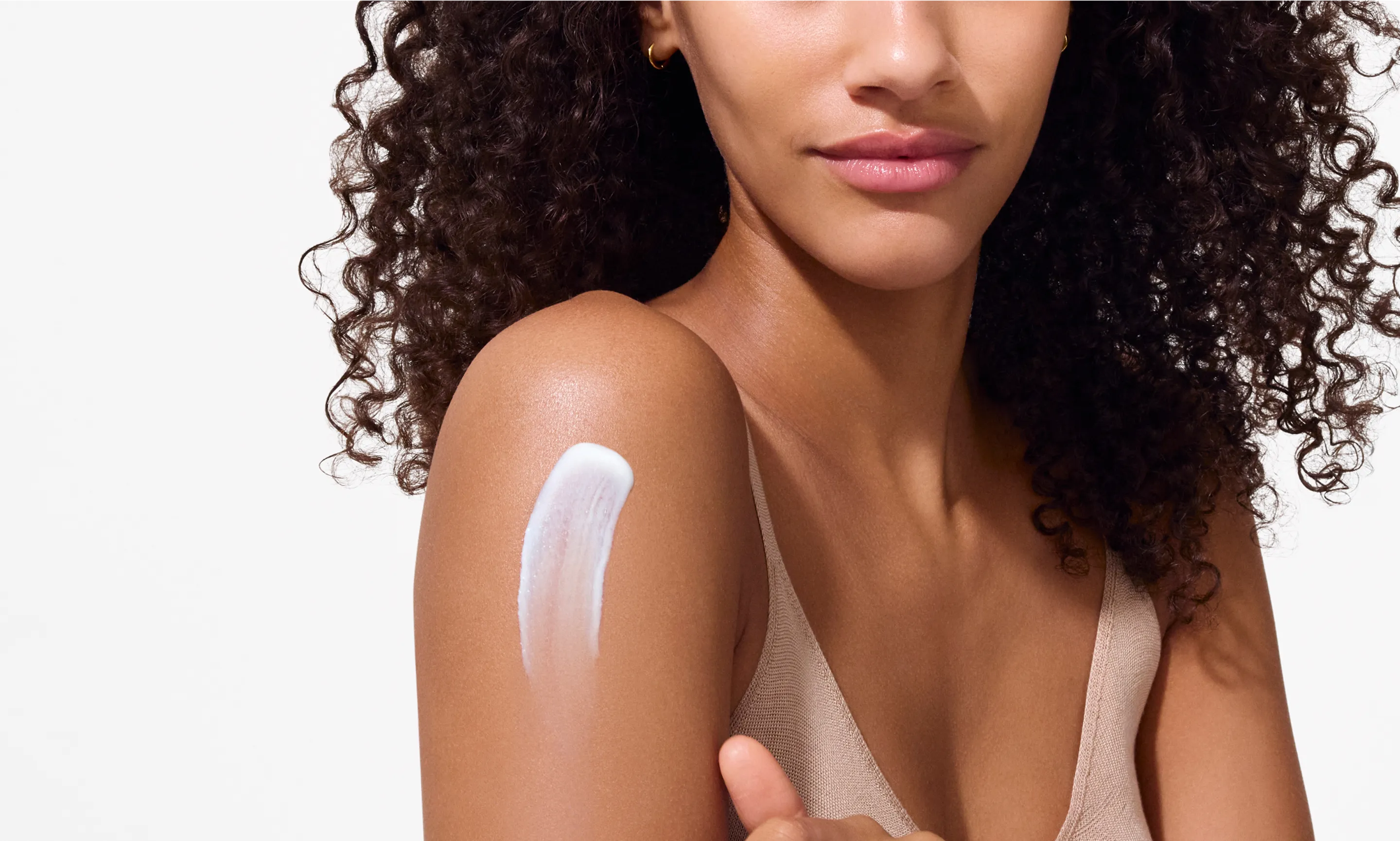 woman applying lotion to shoulder